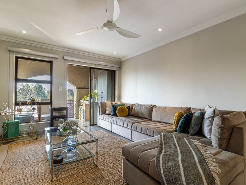A bright and well-maintained living room featuring tiled floors, a modern ceiling fan, and large sliding glass doors leading to an outdoor patio area.