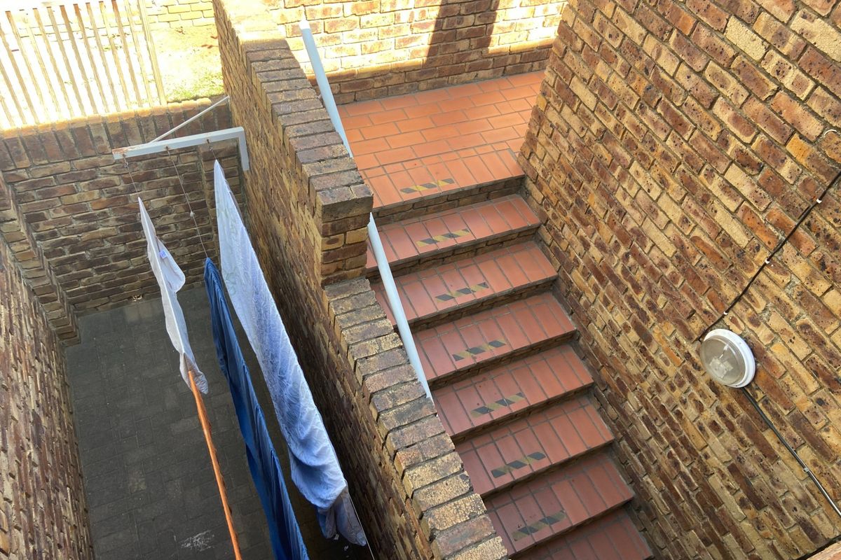 An exterior rear courtyard area featuring a brick staircase with safety treads and a fixed washing line installation.