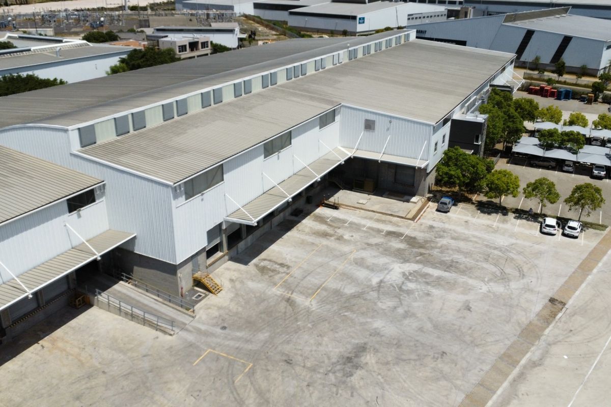 Aerial view of a large industrial warehouse facility featuring extensive concrete yard space, multiple loading docks, and covered parking areas.