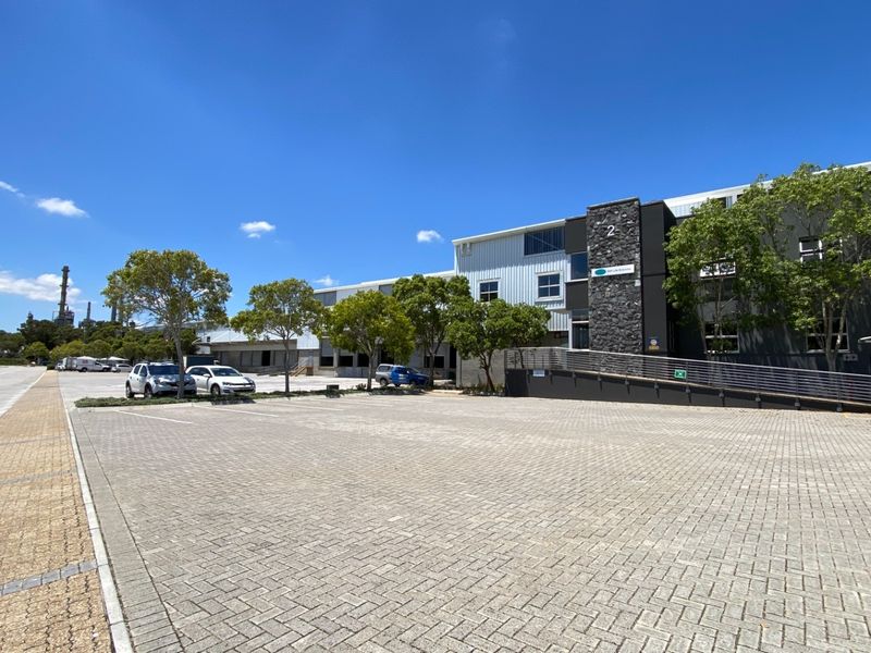 Front exterior view of an industrial property featuring a paved parking area, stone facade accents, and a metal access ramp.