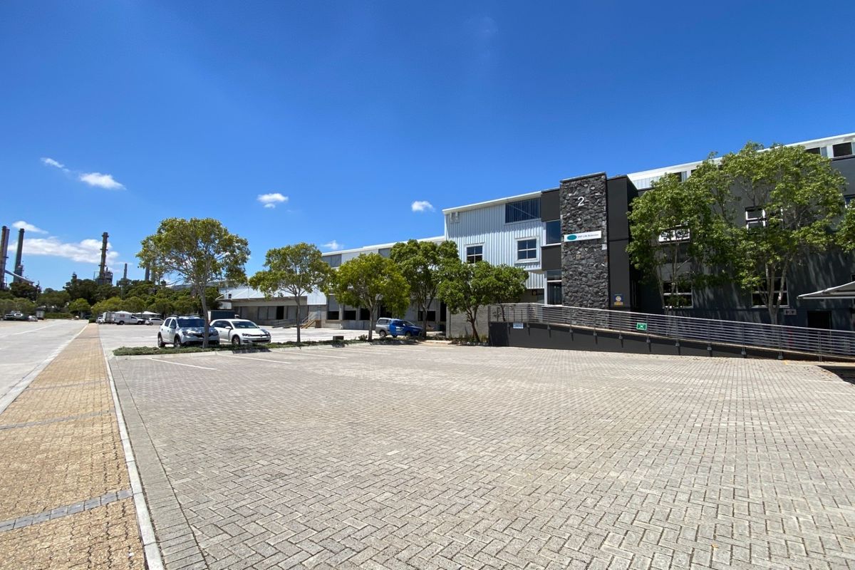 Front exterior view of an industrial property featuring a paved parking area, stone facade accents, and a metal access ramp.