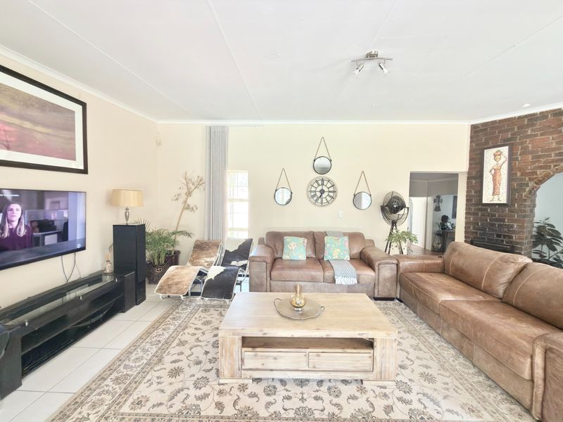 Spacious living room featuring tiled flooring and a prominent exposed brick fireplace, offering a comfortable and inviting atmosphere for relaxation.