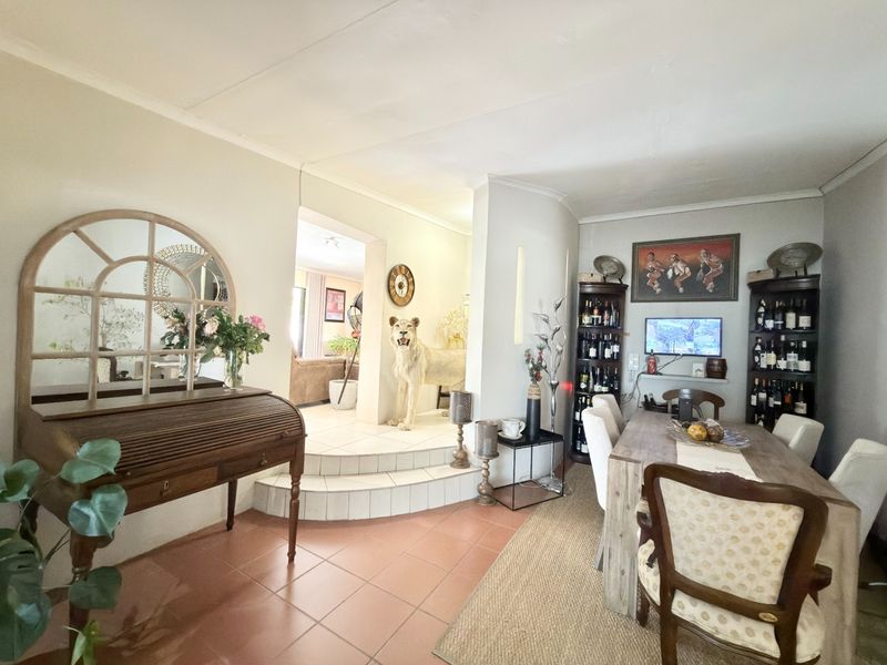 A dining area featuring tiled flooring, a raised platform transition, and coved ceilings, providing a functional space for family meals and entertaining.