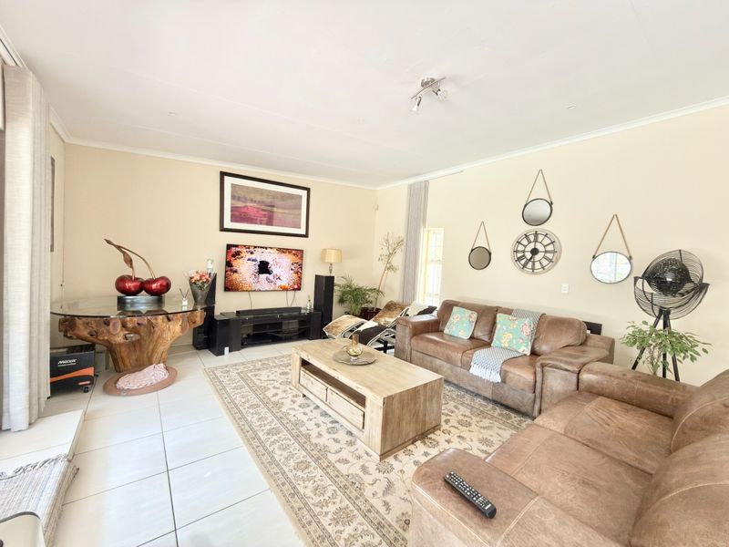 A spacious living room featuring neutral walls, tiled flooring, and recessed ceiling lighting, providing a comfortable and well-maintained area for relaxation.