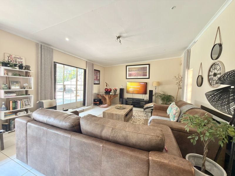A comfortable living room featuring tiled flooring, recessed lighting, and a sliding glass door providing access to the exterior.