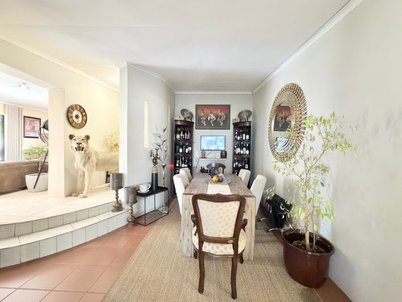 A dining area featuring tiled flooring and a stepped transition to an adjacent living space, with built-in shelving units.