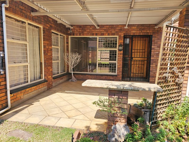 A covered outdoor patio area featuring brick walls, tiled flooring, and a built-in stone counter, providing a functional space for outdoor relaxation.