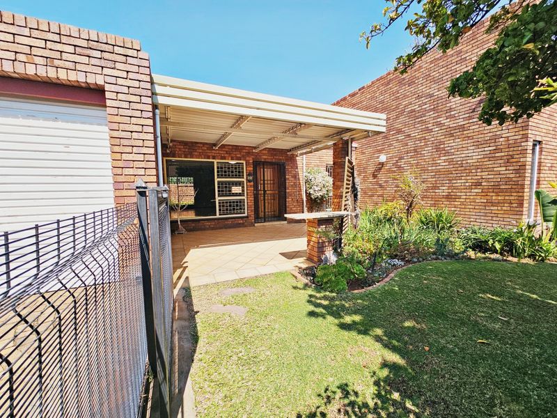 A covered patio area featuring tiled flooring, brick construction, and direct access to the garden and garage.