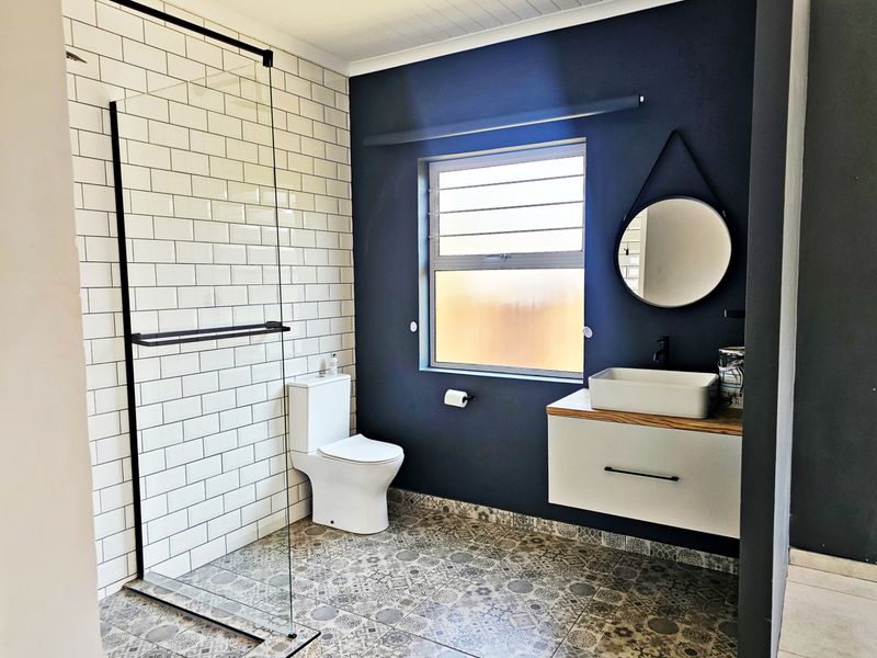 Modern bathroom featuring a walk-in shower with subway tiles, a floating vanity with a vessel sink, and decorative patterned floor tiles.