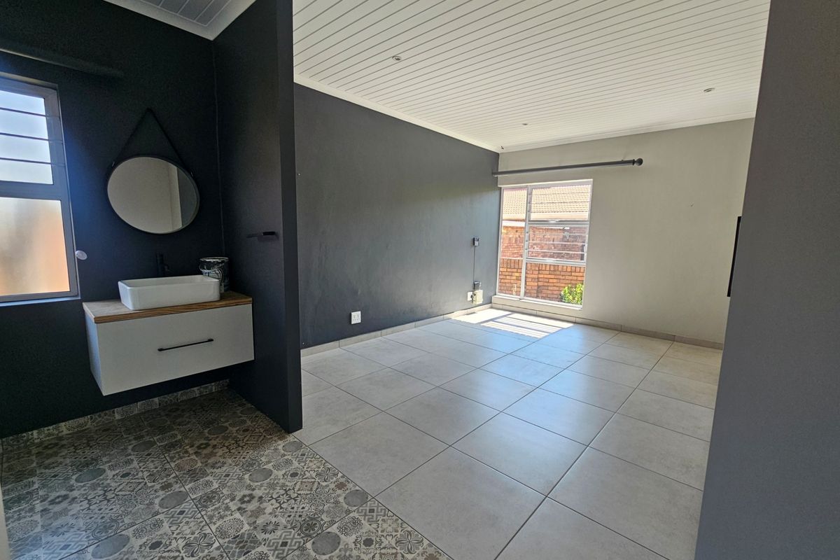 A spacious bedroom featuring a modern floating vanity with a vessel sink, tiled flooring, and a clean, contemporary aesthetic.