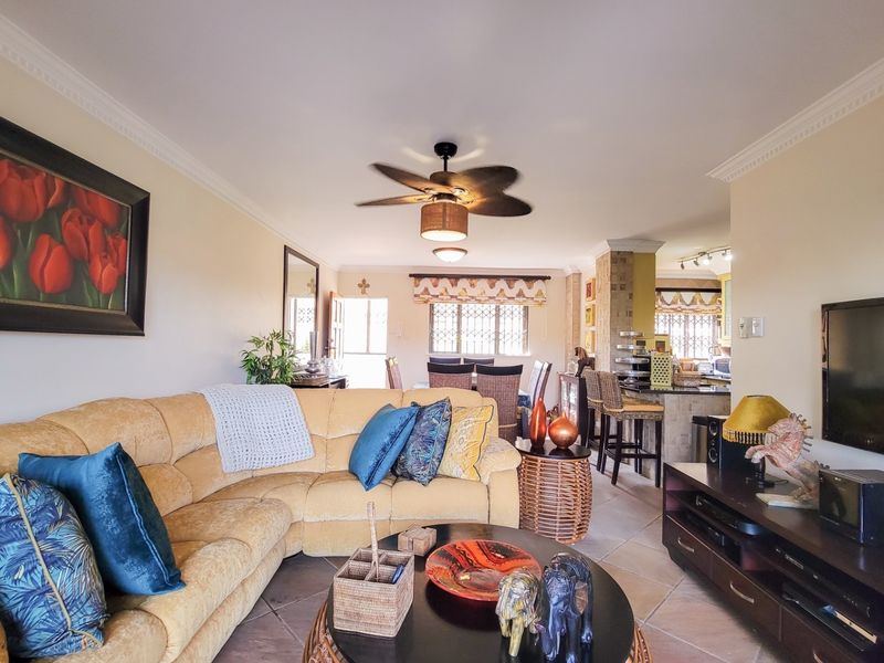 Spacious open-plan living and dining area featuring tiled floors, a ceiling fan, and a breakfast bar connecting to the kitchen.