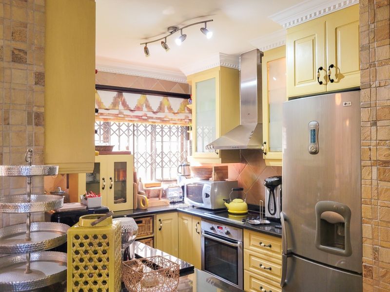 A well-equipped kitchen featuring yellow cabinetry, granite countertops, stainless steel appliances, and decorative stone wall accents, providing a functional and characterful cooking space.