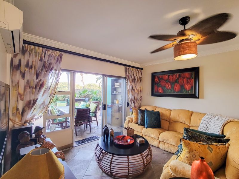 A comfortable living room featuring tiled flooring, a ceiling fan, and a split-system air conditioner, with direct access to an outdoor patio area.
