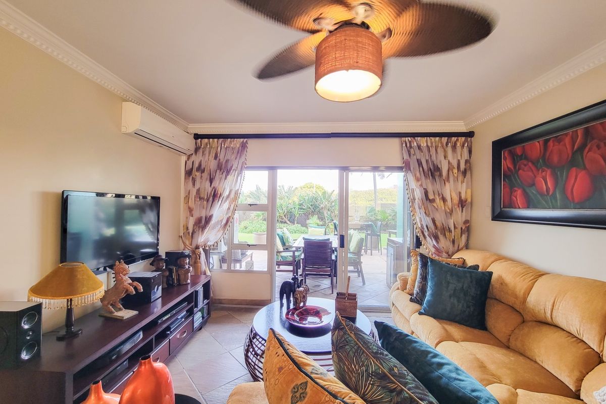 A comfortable living room featuring tiled flooring, crown molding, a ceiling fan, and a split-system air conditioner, with direct access to an outdoor patio.