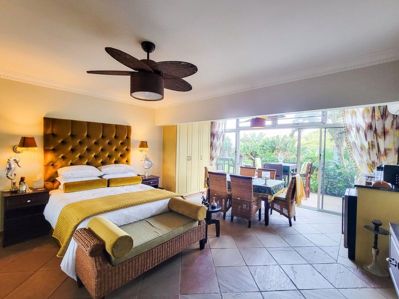 Spacious bedroom featuring tiled flooring, a ceiling fan, built-in cupboards, and large sliding glass doors providing direct access to the outdoor patio area.