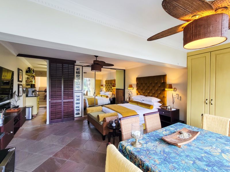 Spacious bedroom featuring tiled flooring, built-in cupboards, and a ceiling fan, with an integrated layout and access to an adjoining area.