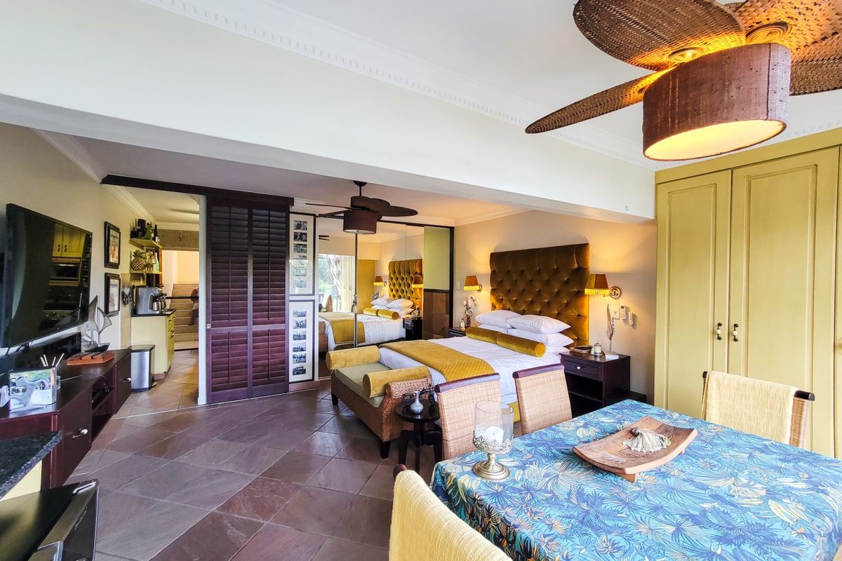 Spacious bedroom featuring tiled flooring, built-in cupboards, and a ceiling fan, with an integrated layout and access to an adjoining area.