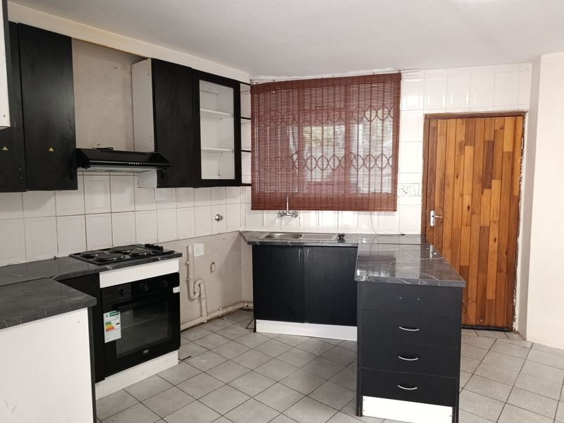 A functional kitchen space featuring built-in cabinetry, an electric oven and hob, and tiled finishes, currently awaiting cosmetic updates and finishing touches.