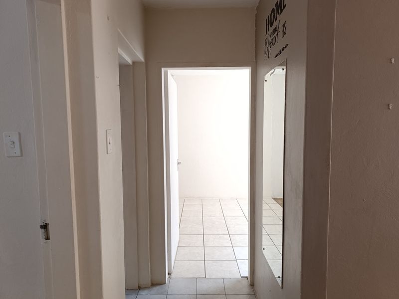 A functional hallway featuring tiled flooring and neutral wall finishes, providing access to adjacent rooms within the apartment.