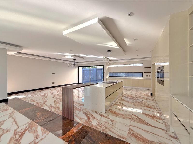 Spacious open-plan living and kitchen area featuring high-end marble-style flooring, modern cabinetry, a central island, and recessed ceiling lighting.