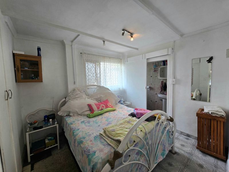 A bedroom featuring tiled flooring, built-in storage, and an en-suite bathroom access point, requiring cosmetic updates to improve the overall finish.