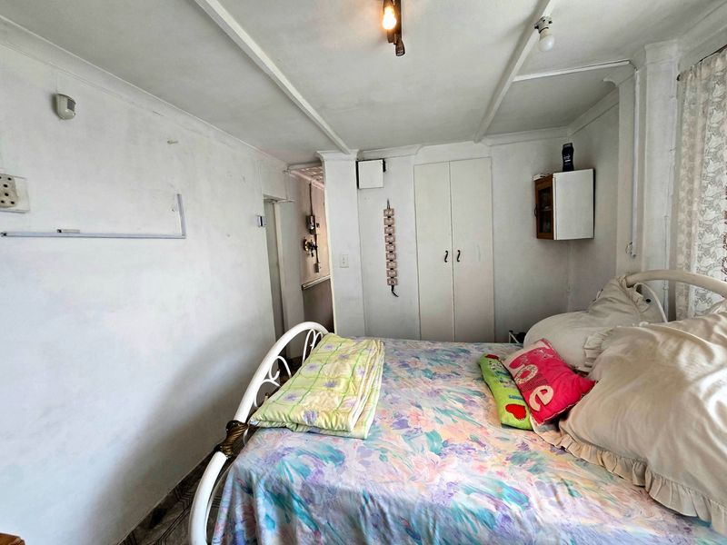 A bedroom featuring built-in wardrobe storage, tiled flooring, and ceiling-mounted lighting. The room requires cosmetic updates to improve its overall condition.