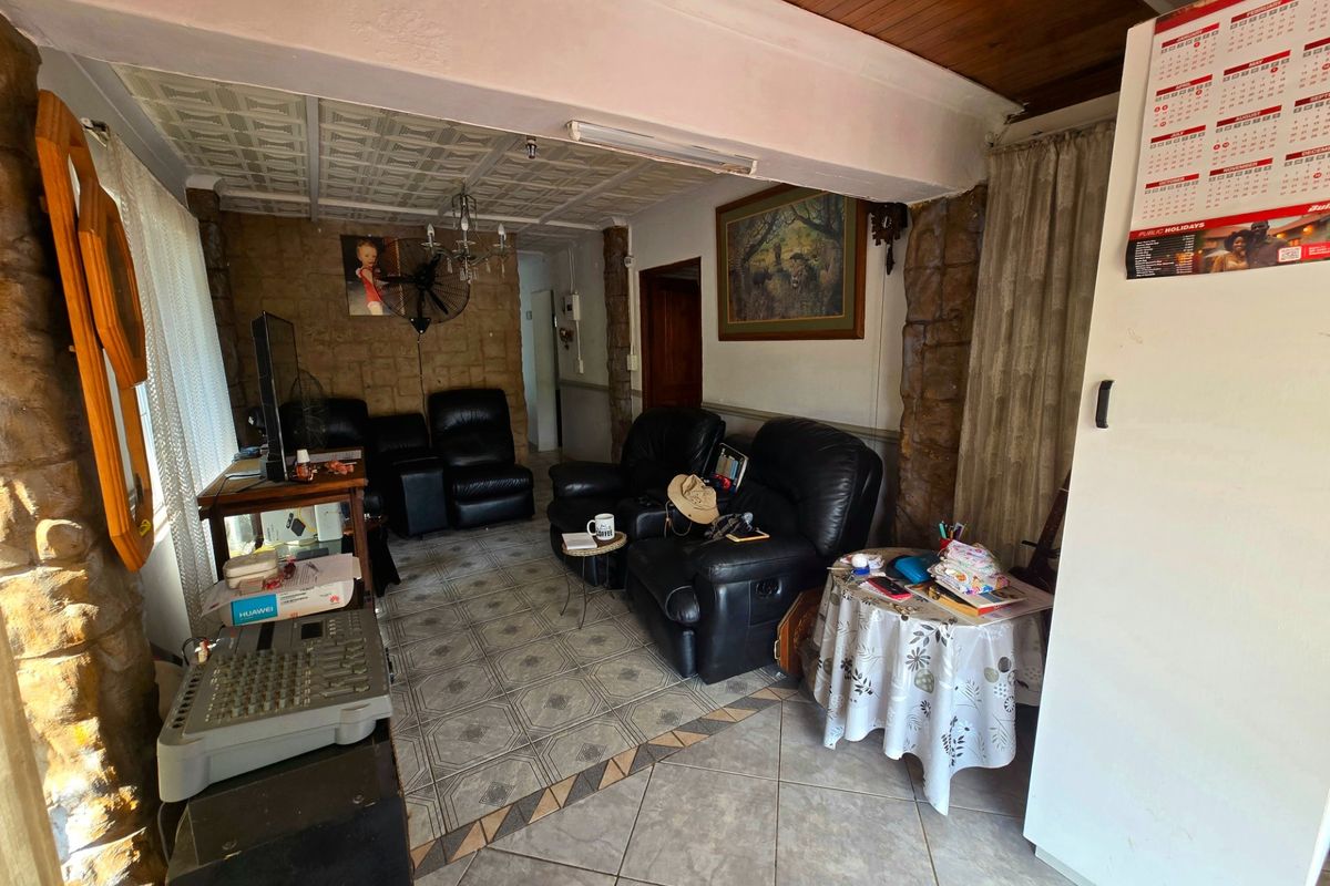 A living area featuring stone-clad pillars, timber ceiling accents, and decorative ceiling tiles, offering a dated aesthetic with potential for modernization.