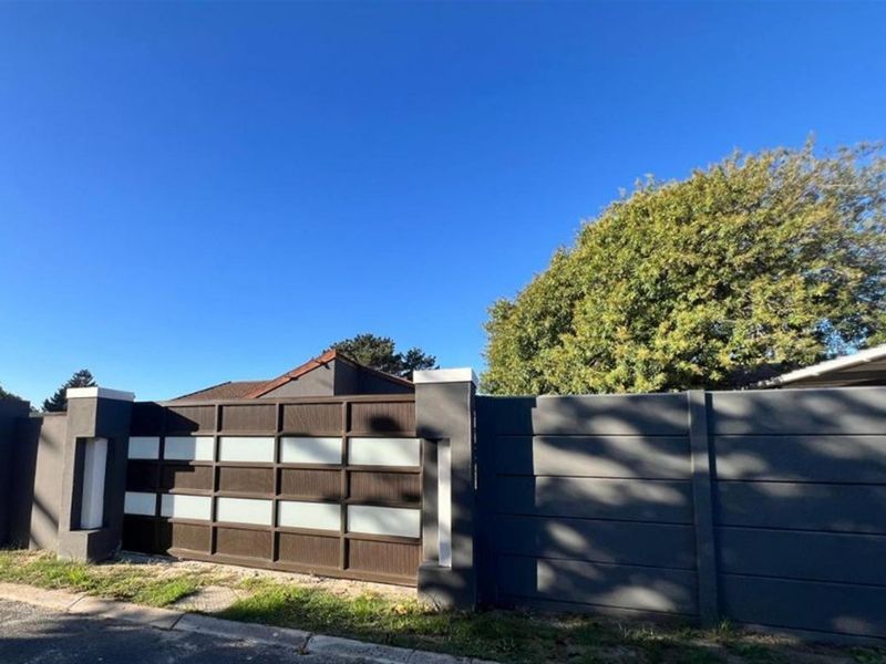 A modern dark grey boundary wall featuring a contemporary sliding gate with horizontal paneling and integrated lighting elements.