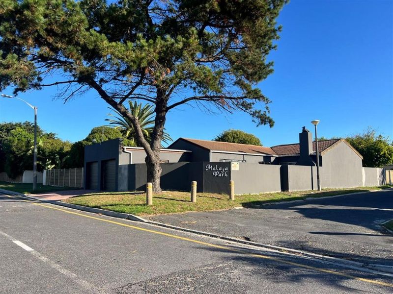 Street view of the property entrance featuring a perimeter wall, double garage, and tiled roof structure.