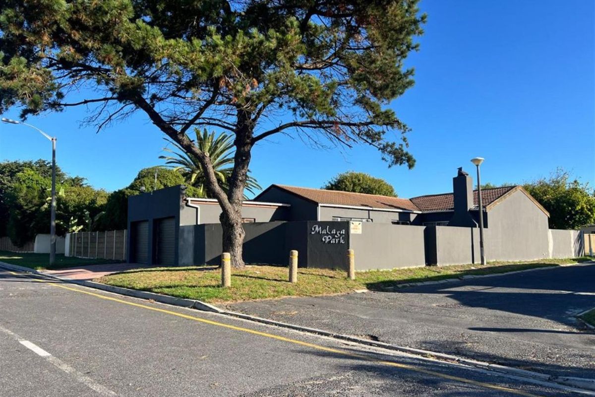 Street view of the property entrance featuring a perimeter wall, double garage, and tiled roof structure.