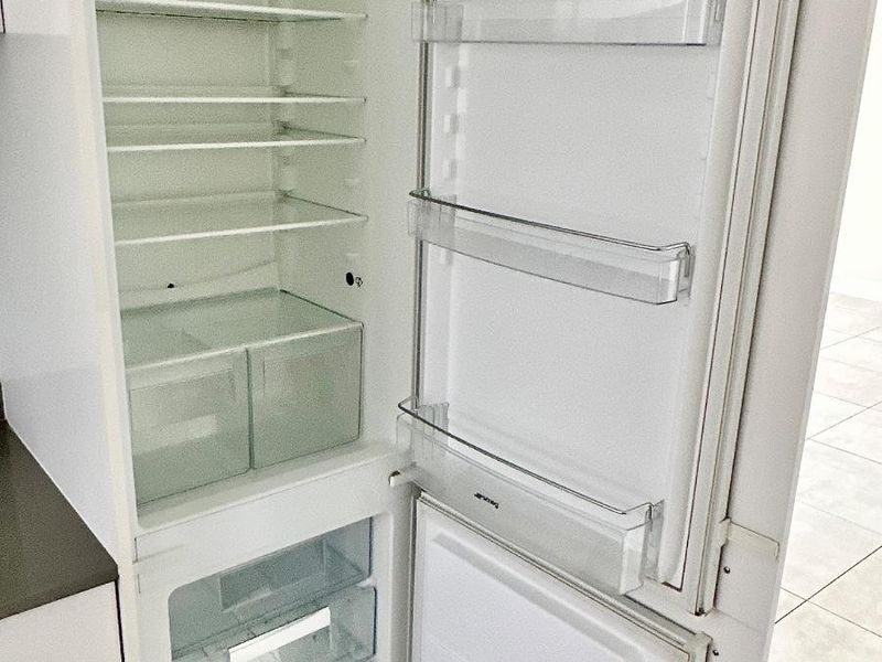 A clean, integrated Smeg refrigerator unit built into the kitchen cabinetry.