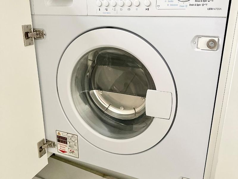 A clean, integrated Smeg washing machine installed within custom cabinetry in a laundry area with tiled flooring.