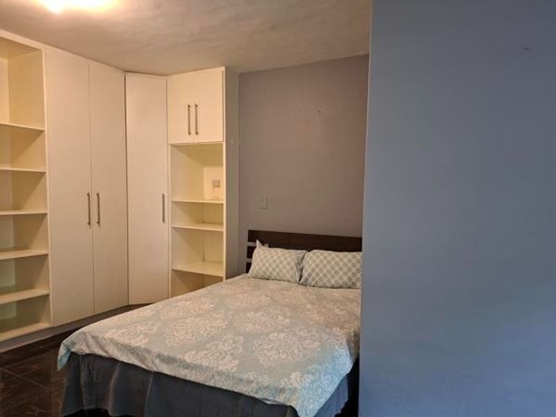 A bedroom featuring extensive built-in cabinetry with integrated shelving and dark tiled flooring.