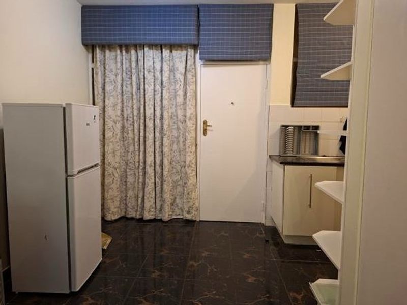A compact kitchen area featuring tiled flooring, built-in cabinetry, and a sink, providing a functional space for meal preparation.
