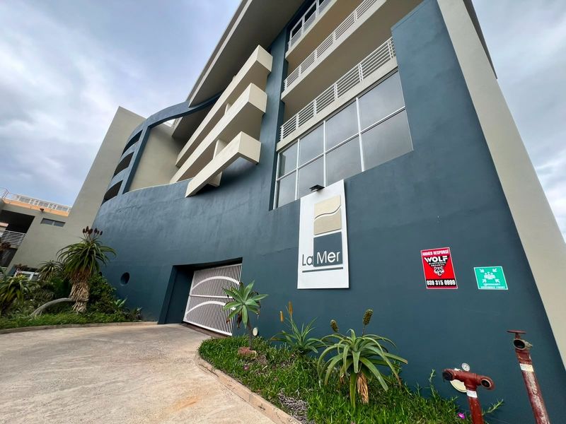 Exterior view of the La Mer apartment building facade, featuring secure gated access, balconies, and established landscaping.