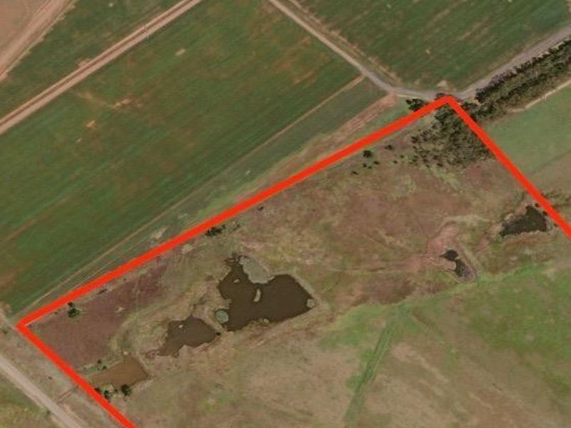 Aerial view of a large farm property featuring open grazing land and natural water dams, outlined in red for boundary identification.