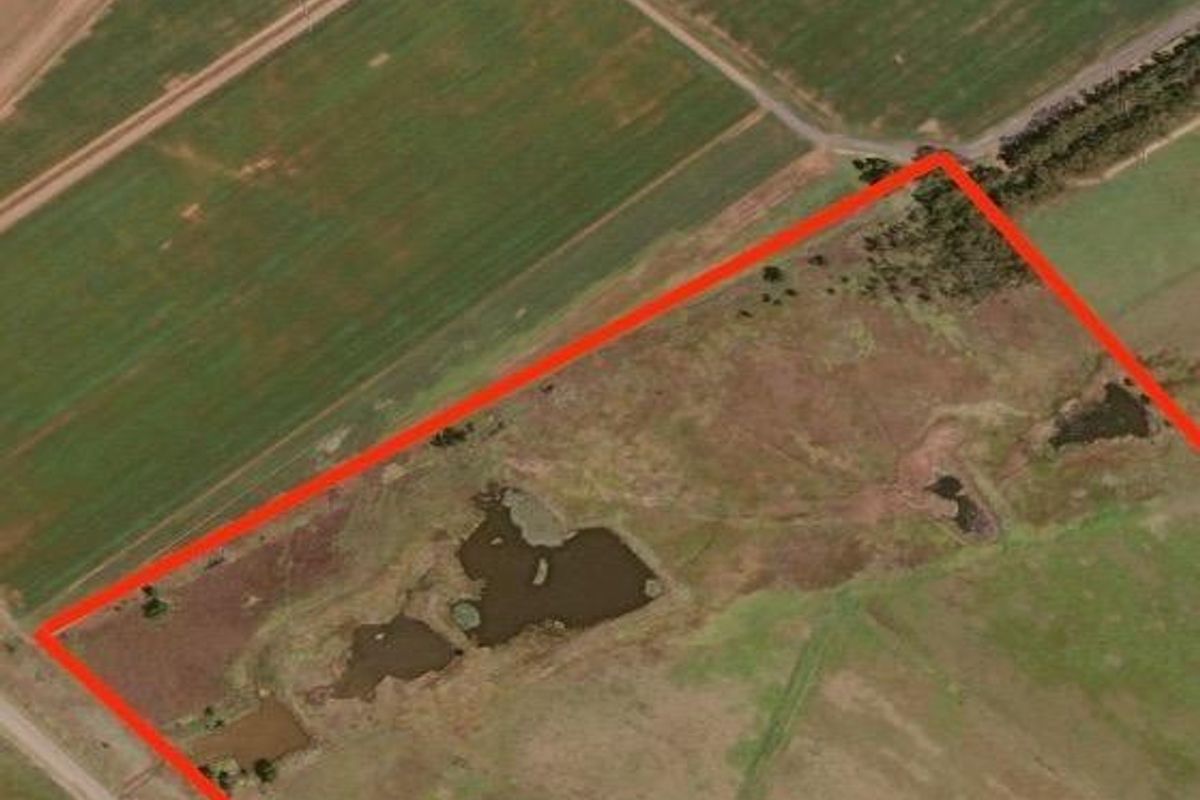 Aerial view of a large farm property featuring open grazing land and natural water dams, outlined in red for boundary identification.