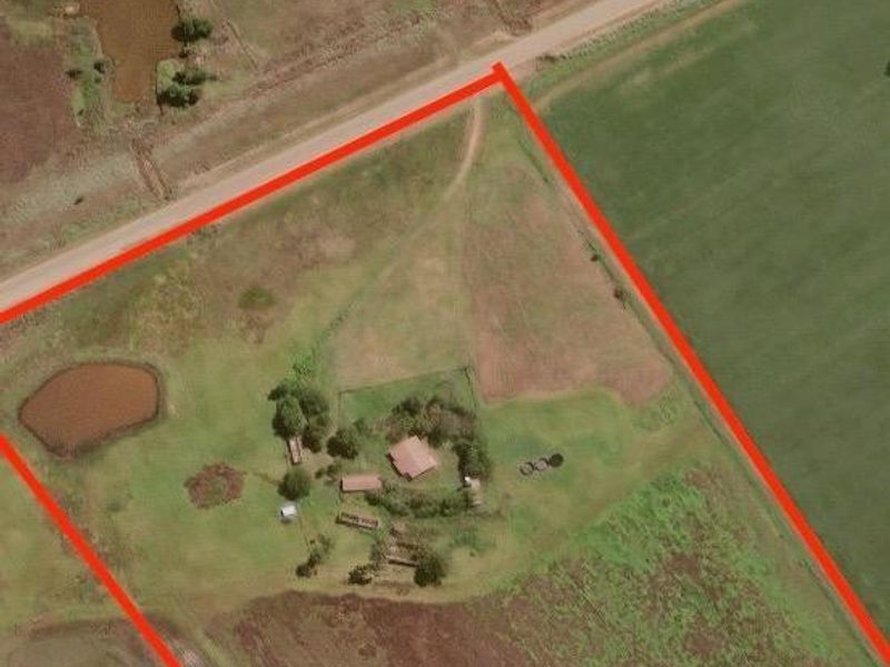 Aerial view of a large farm property featuring open fields, access roads, and water dams, outlined with a red boundary for identification.