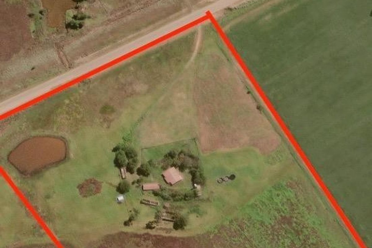 Aerial view of a large farm property featuring open fields, access roads, and water dams, outlined with a red boundary for identification.