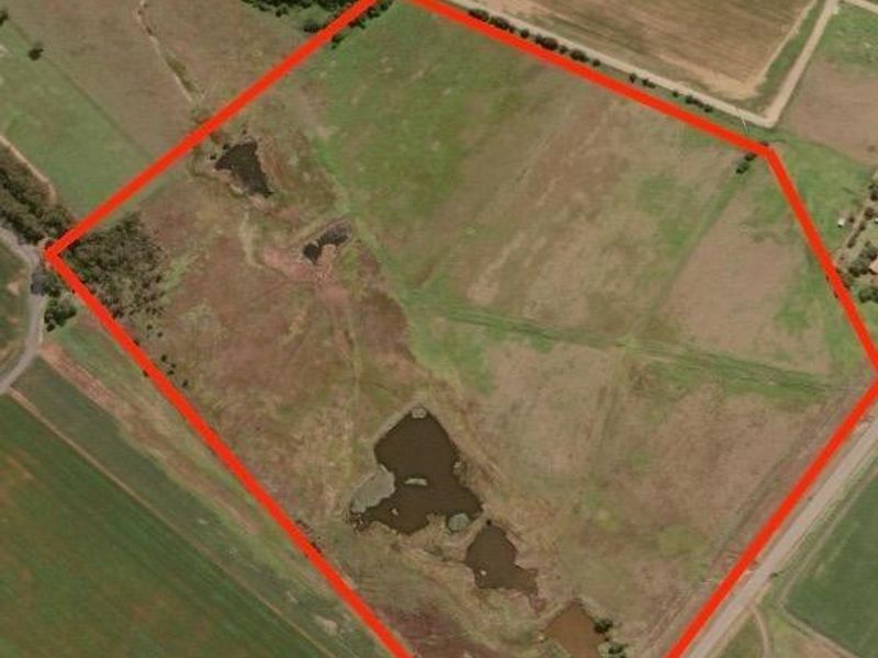 Aerial view of a large farm property featuring open pasture land, established fencing, and multiple natural dams.