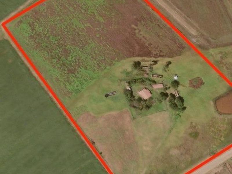 An aerial view of the farm property showing the fenced land boundaries, main dwelling, and surrounding agricultural fields.