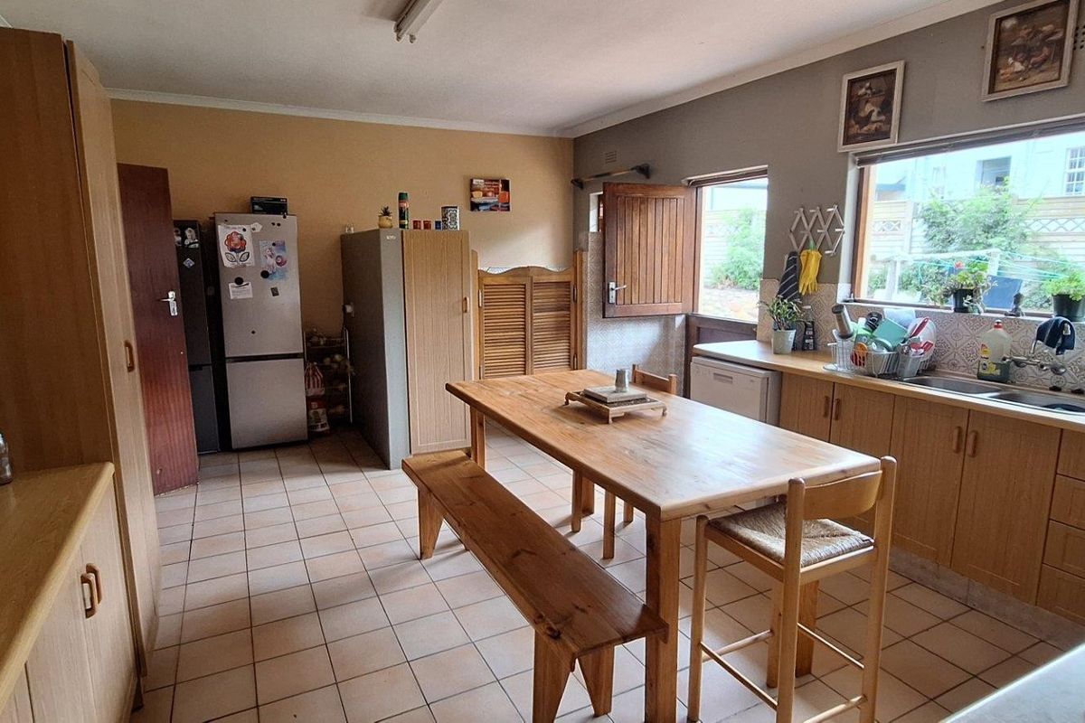 A functional kitchen featuring wood-look cabinetry, tiled flooring, and a large window, offering a practical layout with potential for modern updates.