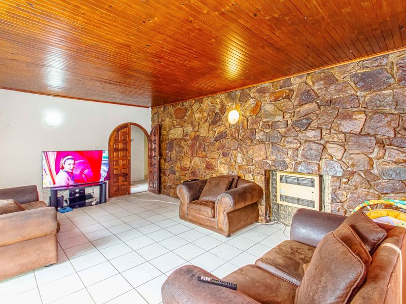 Living room featuring a prominent stone feature wall, timber-clad ceiling, ceramic floor tiles, and a built-in wall heater.
