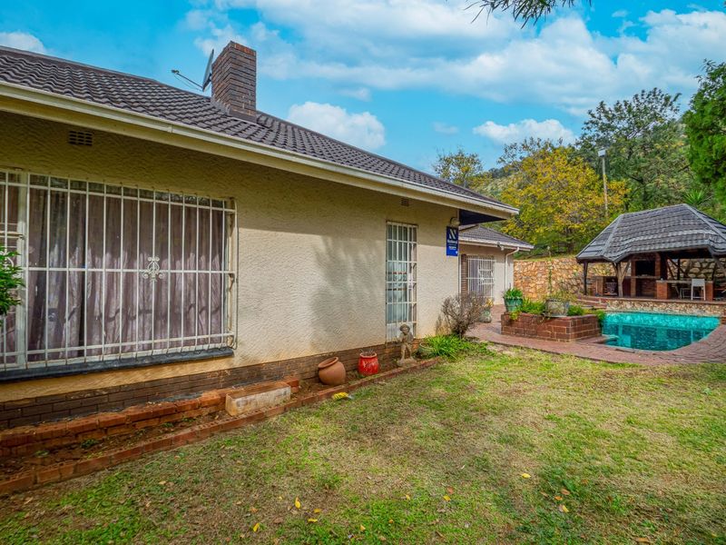 Rear exterior view of the house featuring a swimming pool, a covered lapa area, and a garden space with brick paving.