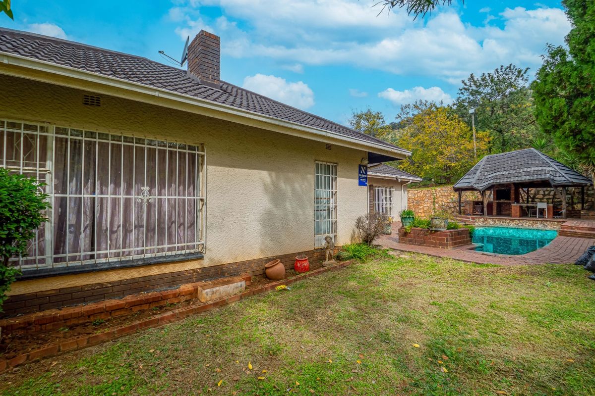 Rear exterior view of the house featuring a swimming pool, a covered lapa area, and a garden space with brick paving.