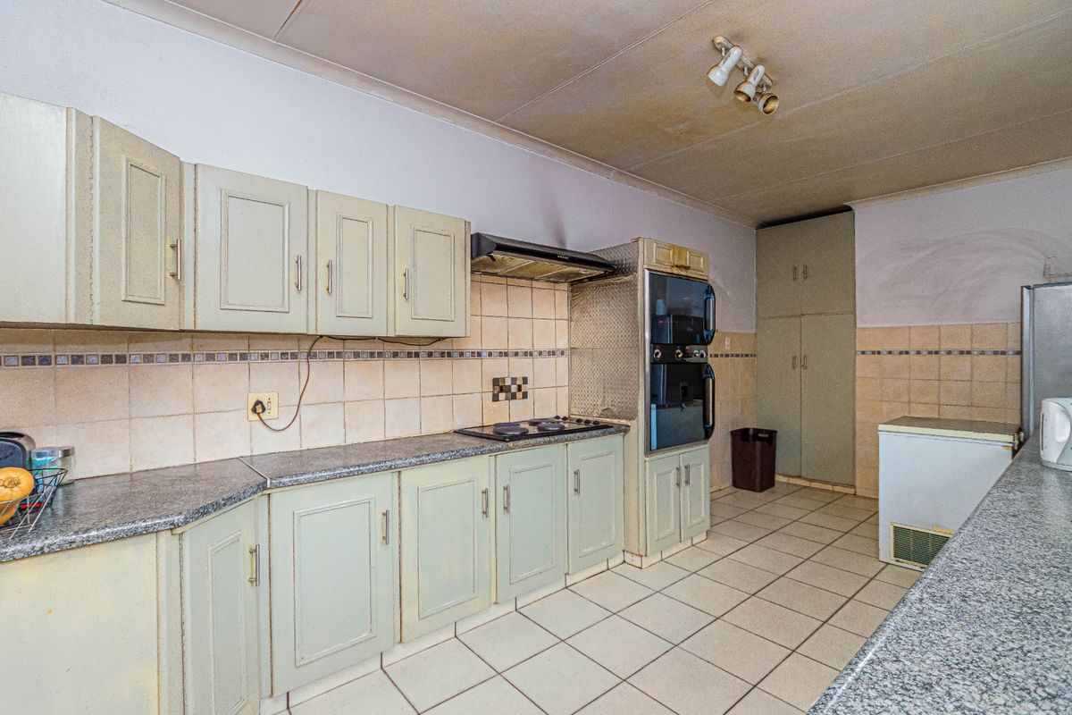 A dated kitchen featuring built-in cabinetry, tiled backsplash, and integrated appliances, requiring cosmetic updates to modernize the space.