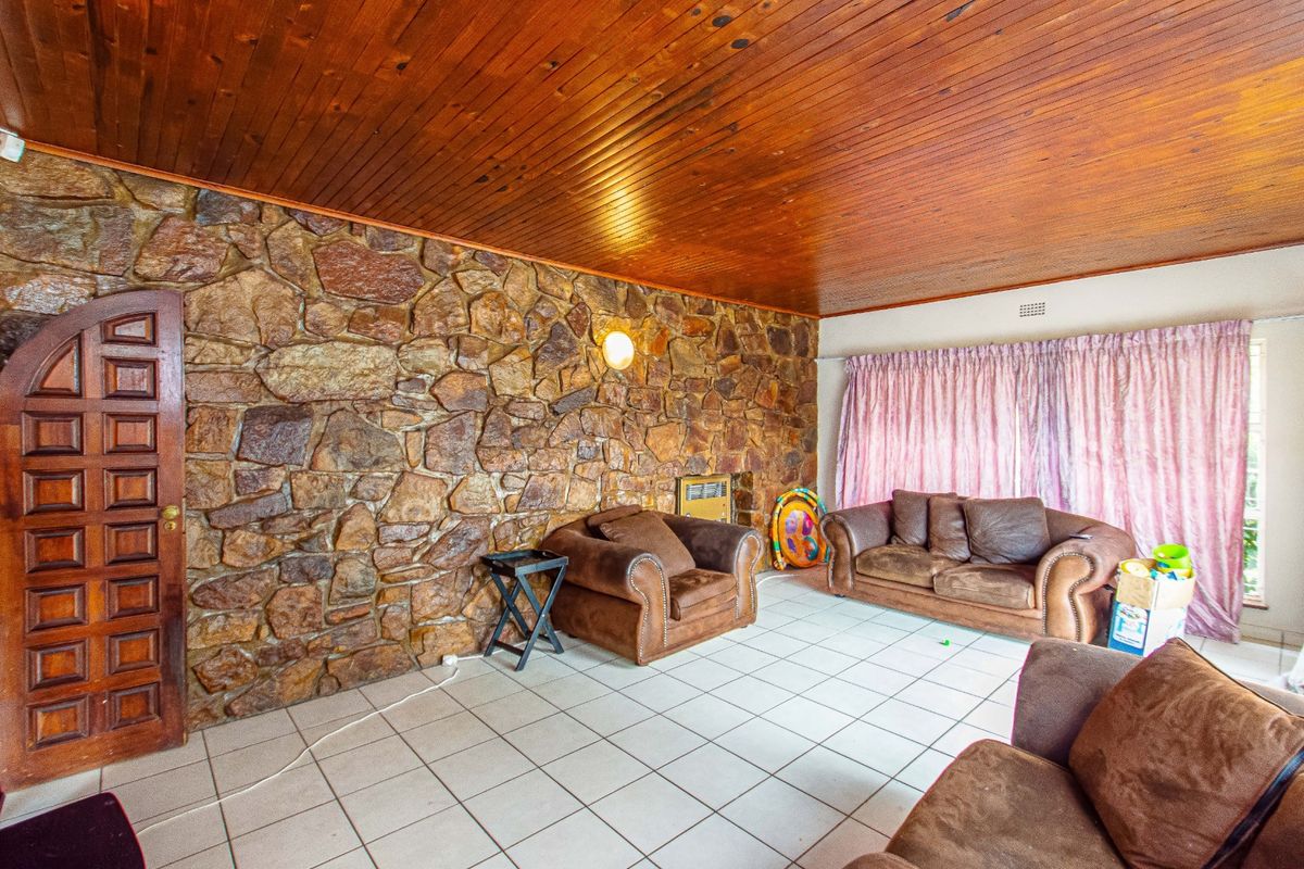 Living room featuring a prominent stone feature wall, timber-clad ceiling, and ceramic tiled flooring with a built-in wall heater.