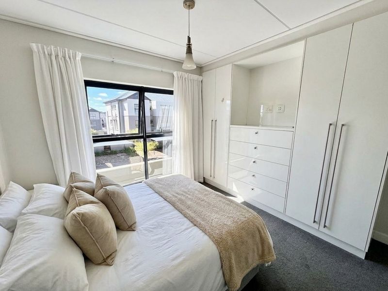 A bright bedroom featuring extensive built-in cabinetry with integrated drawers and a large window providing natural light.