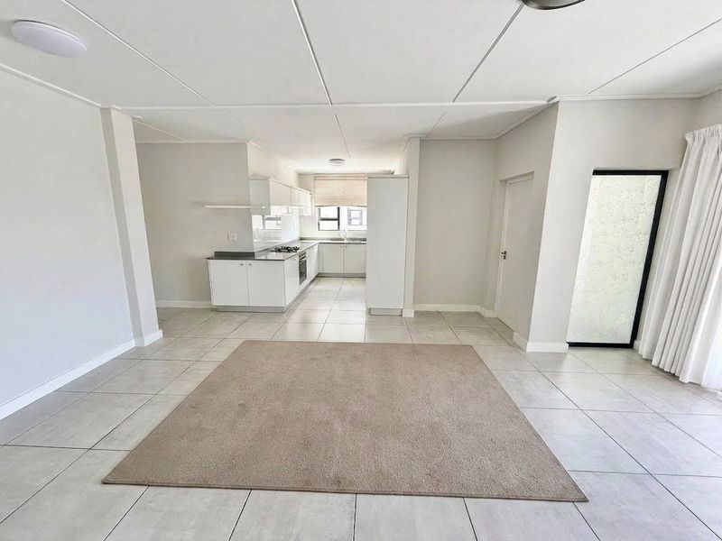 Spacious open-plan living area featuring tiled flooring and a modern kitchen with built-in cabinetry, gas hob, and oven.