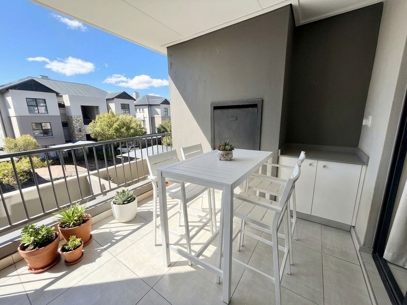 Covered balcony featuring tiled flooring, a built-in braai, and integrated cabinetry, offering a functional outdoor entertainment space.